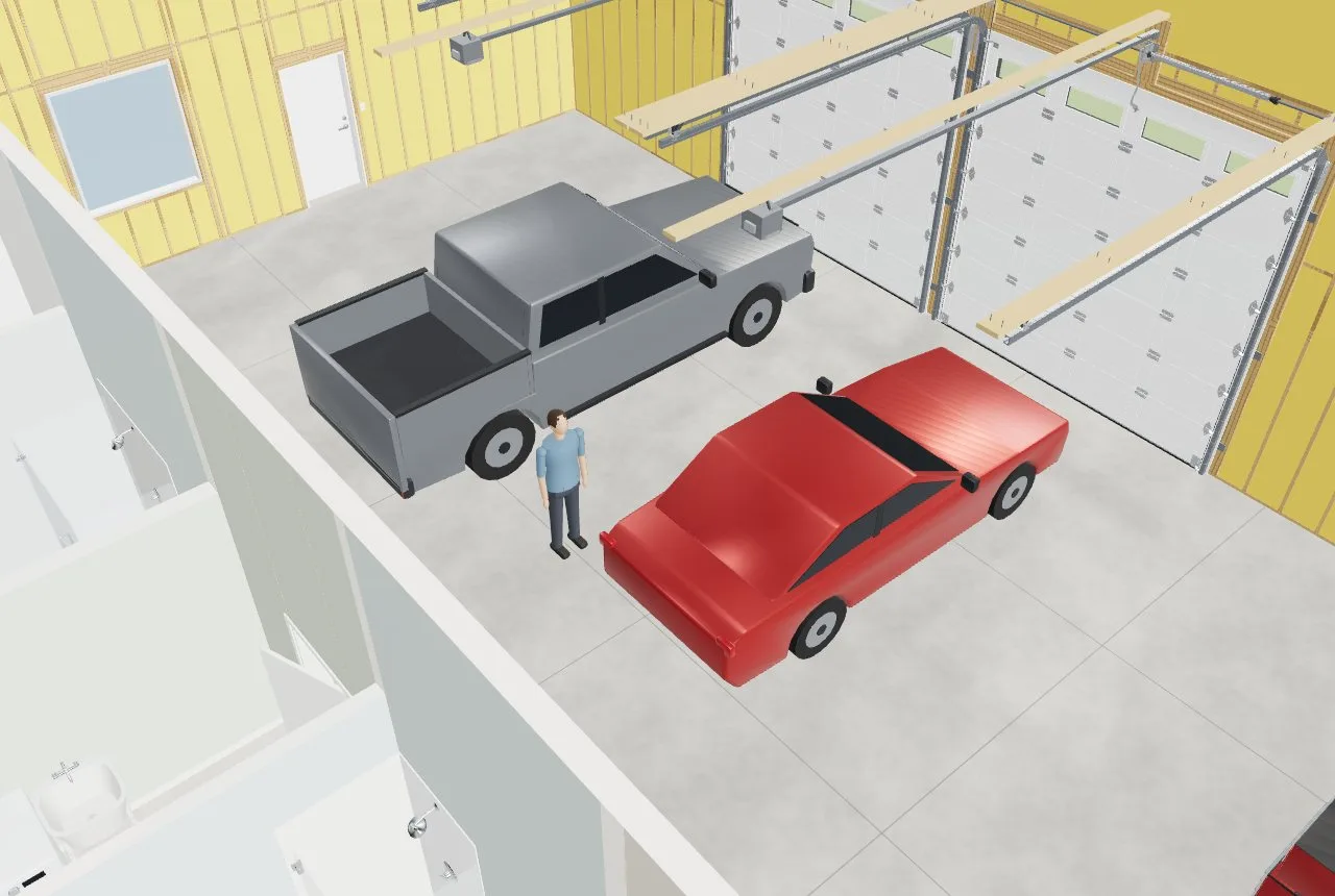 The shop from above: a full-size crew-cab pickup and a sedan parked in front of the overhead doors, with a figure for scale